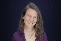 woman wearing a purple shirt smiling at the camera